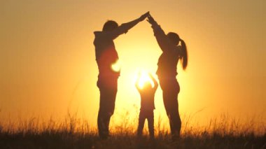 Mutlu aile oyun oynar ve elleriyle bir ev inşa eder, çocuk anne ve babasıyla eğlenir. Çocuklu genç aileler için güvenli ve uygun fiyatlı bir ev kavramı. Çocuklar ve ebeveynler için sıcak bir ev