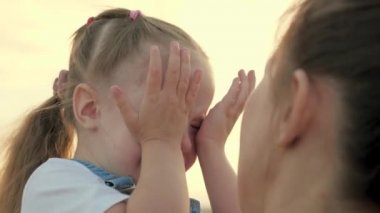 Çocuk parkta, annesinin kollarında ağlıyor. Anne bebeği sakinleştirir. Gözlerinde yaşlarla aile annesi ve çocuğu annelerine duygusal olarak sarılıyorlar. Sevgi dolu genç anne kucaklar ve küçük kızını sakinleştirir.