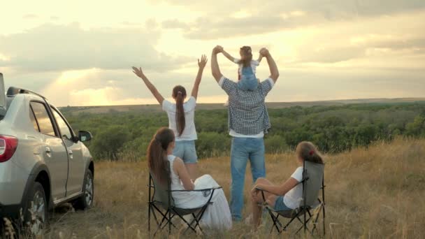 Children and parents are having fun at a halt. happy family, car travel, camping games. friendly family rest in travel chairs, dad and children dance on top of the hill. Family travel concept by car. — Stock Video