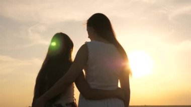 Anne kızına sarılır, onlar güzel gün batımını severler. Çocuk ve çocukların mutlu aile kavramı. Mutlu aile anne ve kızı gün batımında bir tarlada. Anne ve bebek parkta, tarlada, güneşte yürür.