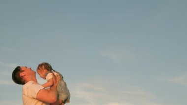 Babam mavi gökyüzüne mutlu bir kız çocuğu fırlatıyor. Mutlu aile yolculukları. Baba ve küçük sağlıklı çocuk birlikte oynar, güler ve sarılırlar. Bebeğin ebeveynin kollarında. Baba izinli. Mutlu aile kavramı.