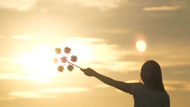 Girl silhouette playing pinwheel park in slow motion. child playing in park catches wind. Happy child playing having fun pinwheel. Happiness vacation childhood children happy family holiday. childhood — Stock Video