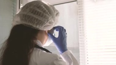 Koruyucu kıyafetli yorgun kadın doktor pencereyi açıyor, tıbbi maskesini çıkarıyor, gözlerini yorgunluktan kapıyor, temiz hava soluyor. Hastanede çok çalışan bir doktor. Salgın Koronovirüs Covid19.