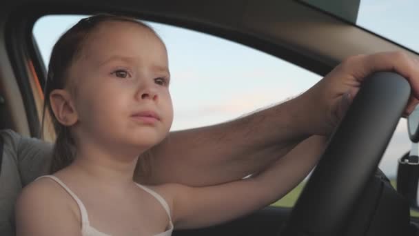 Vater ist mit Kindern im Auto unterwegs. Fahrer und Kind fahren. glückliche Familie und Kindheit Konzept. Papa bringt seiner kleinen Tochter bei, das Lenkrad vom Fahrersitz im Auto zu drehen. — Stockvideo