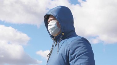 Salgın Koronavirüs. Sokakta maskeli ve kapüşonlu yaşlı bir kadın. Kadın koruyucu maske takıyor. Sağlık konsepti. Koronavirüs N1H1 karantinası, virüs koruması. tehlikeli enfeksiyon