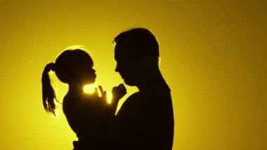 Mutlu baba ve küçük çocuk parkta güneşin altında doğada sarılıyorlar. Babası sevgili sağlıklı kızını kollarında tutuyor. Gün batımında baba ve çocuğun silueti. Aile tatilde..