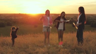 Sağlıklı çocuklar ve anne oynar, saksocu çocuk sabun köpüğü yakalar. Anne ve kız kardeşler gün batımında parkta birlikte oynuyorlar. Mutlu aile ve çocukluk kavramı. Güneşli hava kabarcıkları, çocukların doğum günleri