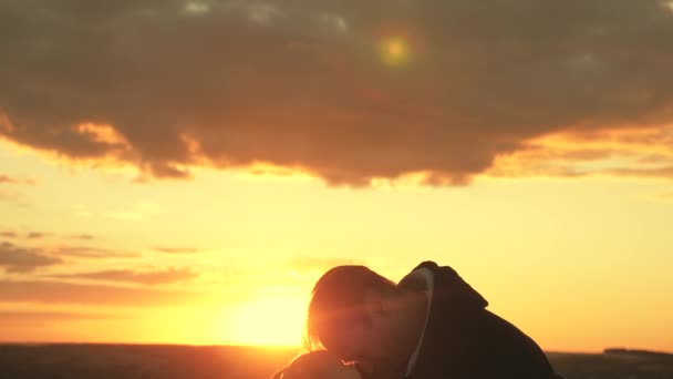 Papá abraza besos y cubre a su hija pequeña con una chaqueta en la noche fresca en el parque al atardecer. El niño y el padre felices juegan en el campo bajo el sol. niño sano ama a papá. familia feliz y la infancia — Vídeos de Stock