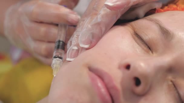 Una donna ottiene trattamenti cosmetici per il viso. Iniezioni di collagene botox. gioventù e concetto di bellezza. le mani dei cosmetologi nei guanti medici fanno un'iniezione nella pelle di un viso femminile. Clinica di bellezza. — Video Stock