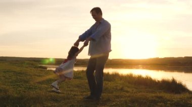 Neşeli çocuk babasıyla dışarıda oynuyor. Babacık mutlu çocuğun elleri için parktaki günbatımının ışınlarında dönüyor. Küçük kızım güneşli plajda babasıyla oynuyor. Tatilde mutlu bir aile.