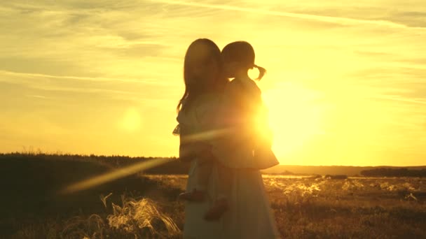 Matka bawi się zdrowym dzieckiem w ramionach w parku na słońcu. Mama i córka przytulają się. Wesołe dziecko bawiące się z matką o zachodzie słońca. szczęśliwa wolna rodzina podróżująca na wakacje — Wideo stockowe