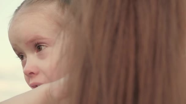 Mama kalmeert de baby. Het kind huilt in het park in de armen van mama. familie moeder en kind met tranen in hun ogen knuffelt hun moeder, emotioneel. liefdevolle jonge moeder knuffelt en kalmeert haar dochtertje. — Stockvideo