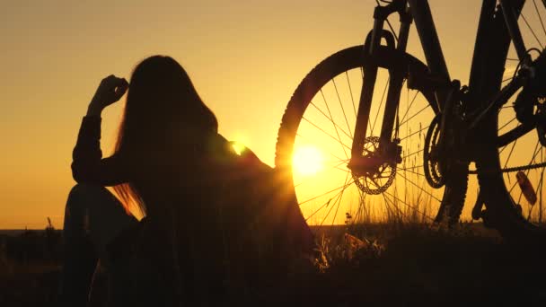 Dziewczyna podróżuje z rowerem o zachodzie słońca. Chodzenie samemu podczas pandemii. Koncepcja przygody i podróży. Zdrowa młoda kobieta turystka siedzi na wzgórzu obok roweru ciesząc się naturą i słońcem — Wideo stockowe