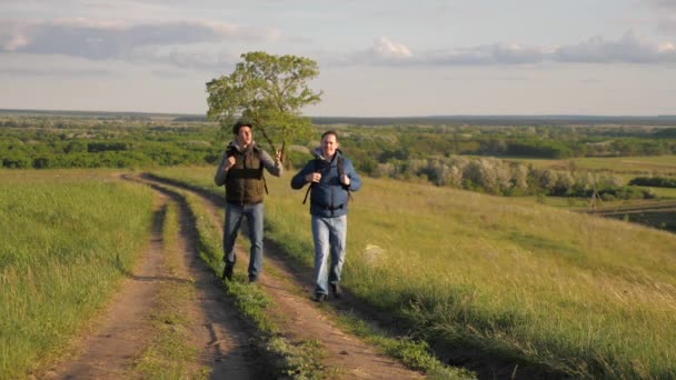 Reizigers met rugzakken lopen langs de weg. Teamwork. Avontuur en reizen concept. Toeristen genieten van ontspanning en natuur — Stockvideo