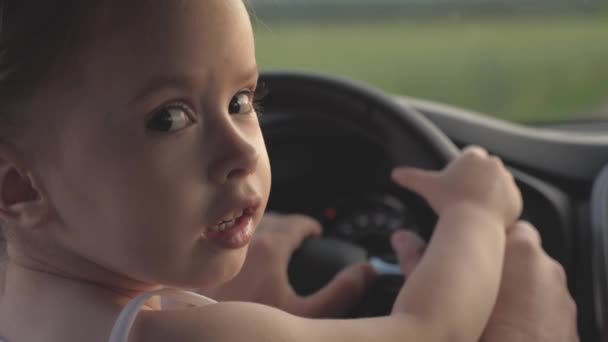 Tata uczy swoją córeczkę obracać kierownicą siedząc w samochodzie na fotelu kierowcy. Ojciec podróżuje z dziećmi samochodem. Kierowca i dziecko prowadzą. szczęśliwa rodzina i koncepcja dzieciństwa — Wideo stockowe