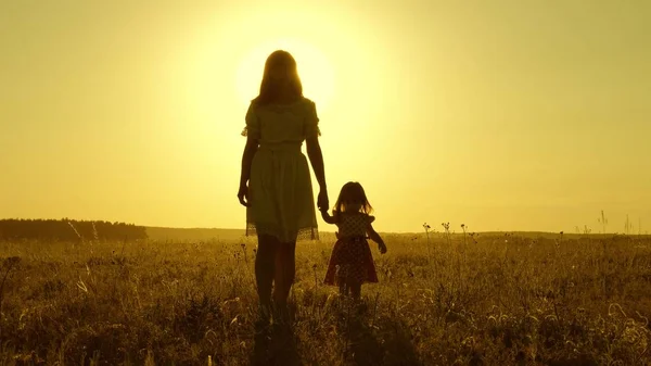 Mama Camina En El Campo Con Su Hija Pequena Al Atardecer Bebe Toma La Mano De Mama Camina En El Campo Con Su Hija Pequena Al Atardecer Bebe Toma La Mano De