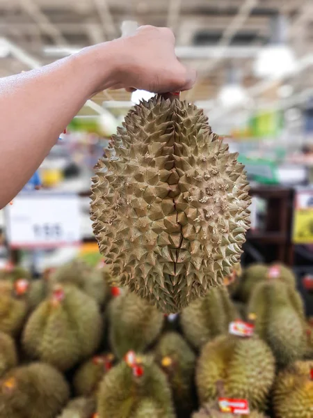 Левая рука держа Durian, Durian для продажи в супермаркете, ки — стоковое фото