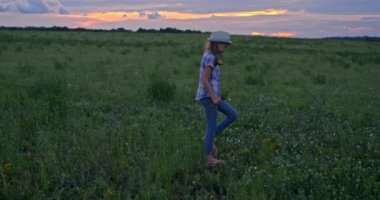 Çiçekli bir kızın güzel yeşil tarlada yürüdüğü görüntüler.