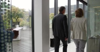 Altı kişilik bir grup, iyi aydınlatılmış bir ofisin koridorunda yürüyor.