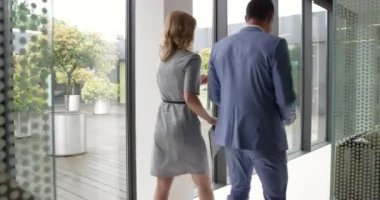 Altı iş adamından oluşan bir grup, arka kamerayla ofisin kapısından geçiyor.