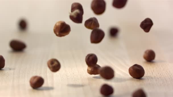 木製のテーブルの上に落ちるヘーゼルナッツの山 スローモーション — ストック動画