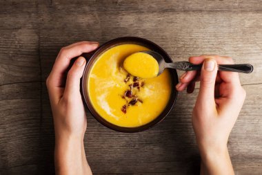 Eski ahşap masa balkabağı çorbası. Bir kaşık ile eller.