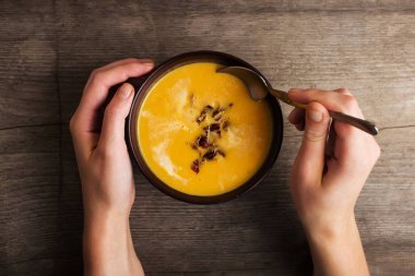 Eski ahşap masa balkabağı çorbası. Bir kaşık ile eller.