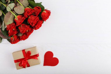 Bir buket kırmızı gül, hediye ve beyaz ahşap masa kalpler. Kavram kadın gün ya da St. Valentine. Kopya alanı.