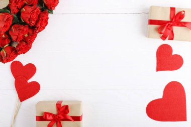 Bir buket kırmızı gül, hediye ve beyaz ahşap masa kalpler. Kavram kadın gün ya da St. Valentine. Kopya alanı.