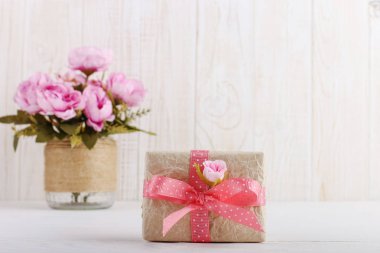 Vazo pembe çiçekler ve masada zanaat kağıt hediye. Kadınlar Günü veya Sevgililer Günü Kavramı.