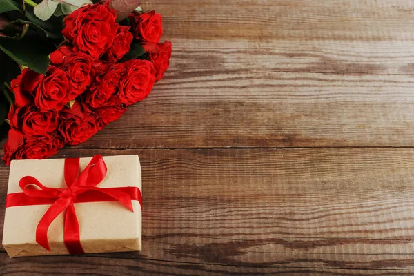 A bouquet of red roses, gift on wooden table. Concept Women\'s Day or St. Valentine. Copy space.