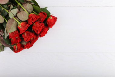 Red roses bouquet on white wooden table. Concept Women's Day or St. Valentine. Copy space.
