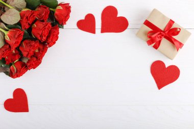Bir buket kırmızı gül, hediye ve beyaz ahşap masa kalpler. Kavram kadın gün ya da St. Valentine. Kopya alanı.