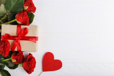 Bir buket kırmızı gül, hediye ve beyaz ahşap masa kalpler. Kavram kadın gün ya da St. Valentine. Kopya alanı.