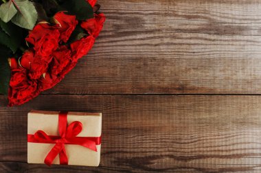 Bir buket kırmızı gül, ahşap masa hediye. Kavram kadın gün ya da St. Valentine. Kopya alanı.
