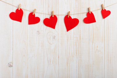 İp ile clothespins, Beyaz ahşap zemin üzerinde kırmızı kalpler. Metin, kopya alanı için yer.