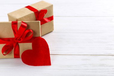 Kırmızı kurdele ve beyaz ahşap zemin üzerinde kalpleri ile Hediyelik kullanır. Kadınlar Sevgililer günü. Metin, kopya alanı için yer.