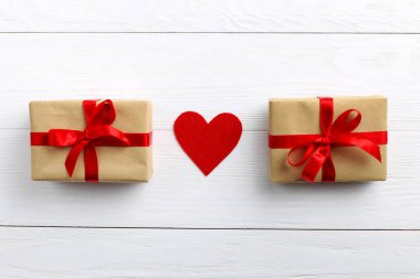 Kırmızı kurdele ve beyaz ahşap zemin üzerinde kalpleri ile Hediyelik kullanır. Kadınlar Sevgililer günü. Metin, kopya alanı için yer.