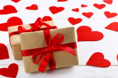 Kırmızı kurdele ve beyaz ahşap zemin üzerinde kalpleri ile Hediyelik kullanır. Kadınlar Sevgililer günü. Metin, kopya alanı için yer.