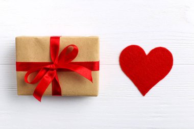 Kırmızı kurdele ve beyaz ahşap zemin üzerinde kalpleri ile Hediyelik kullanır. Kadınlar Sevgililer günü. Metin, kopya alanı için yer.
