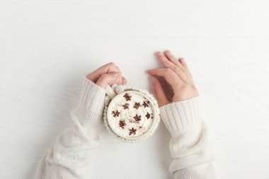 Kız sıcak kış içeceği bir fincan tutuyor, yıldız şeklinde krem şanti ve toz ile. Parlak renklerde Noel konsepti. Kopyalama alanı.