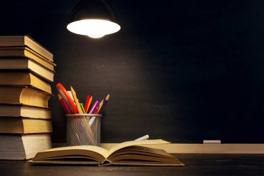 Öğretmenin masası ya da bir işçi, hangi yazı malzemeleri yalan, bir kitap, akşam lamba altında. Okul teması için metin veya arka plan için boş. Kopyalama alanı.