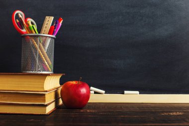 Yazma malzemeleri, bir kitap ve bir elma, metin için boş veya bir okul teması için bir arka plan ile Öğretmen masası. Kopyalama alanı.