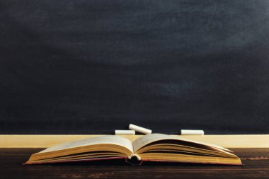 Kitaplar tebeşir tahtasının arka planında yatıyor. Çalışma kavramı veya öğretmenin günü. Kopyalama alanı.