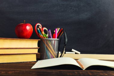 Yazma malzemeleri, bir kitap ve bir elma, metin için boş veya bir okul teması için bir arka plan ile Öğretmen masası. Kopyalama alanı.