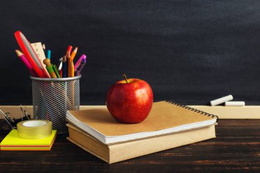 Yazma malzemeleri, bir kitap ve bir elma, metin için boş veya bir okul teması için bir arka plan ile Öğretmen masası. Kopyalama alanı.