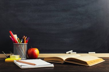 Yazma malzemeleri, bir kitap ve bir elma, metin için boş veya bir okul teması için bir arka plan ile Öğretmen masası. Kopyalama alanı.