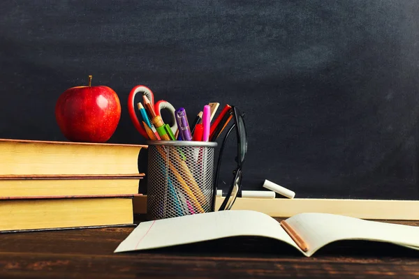 Yazma malzemeleri, bir kitap ve bir elma, metin için boş veya bir okul teması için bir arka plan ile Öğretmen masası. Kopyalama alanı.
