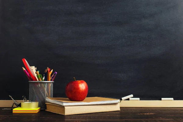 Yazma malzemeleri, bir kitap ve bir elma, metin için boş veya bir okul teması için bir arka plan ile Öğretmen masası. Kopyalama alanı.
