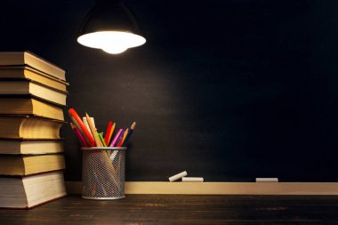 Öğretmenin masası ya da bir işçi, hangi yazı malzemeleri yalan, bir kitap, akşam lamba altında. Okul teması için metin veya arka plan için boş. Kopyalama alanı.
